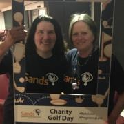 Charity - Maria and a friend using the charity golf day frame