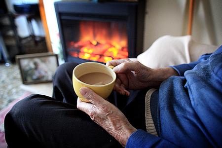 Clacton and Frinton Gazette: BRIDGWATER, ENGLAND - OCTOBER 03:  In this photo illustration, an elderly man warms himself in front of a fire on October 6, 2011 in Bristol, England. Energy price rises and an increase in the cost of living has resulted in more people, including the elde